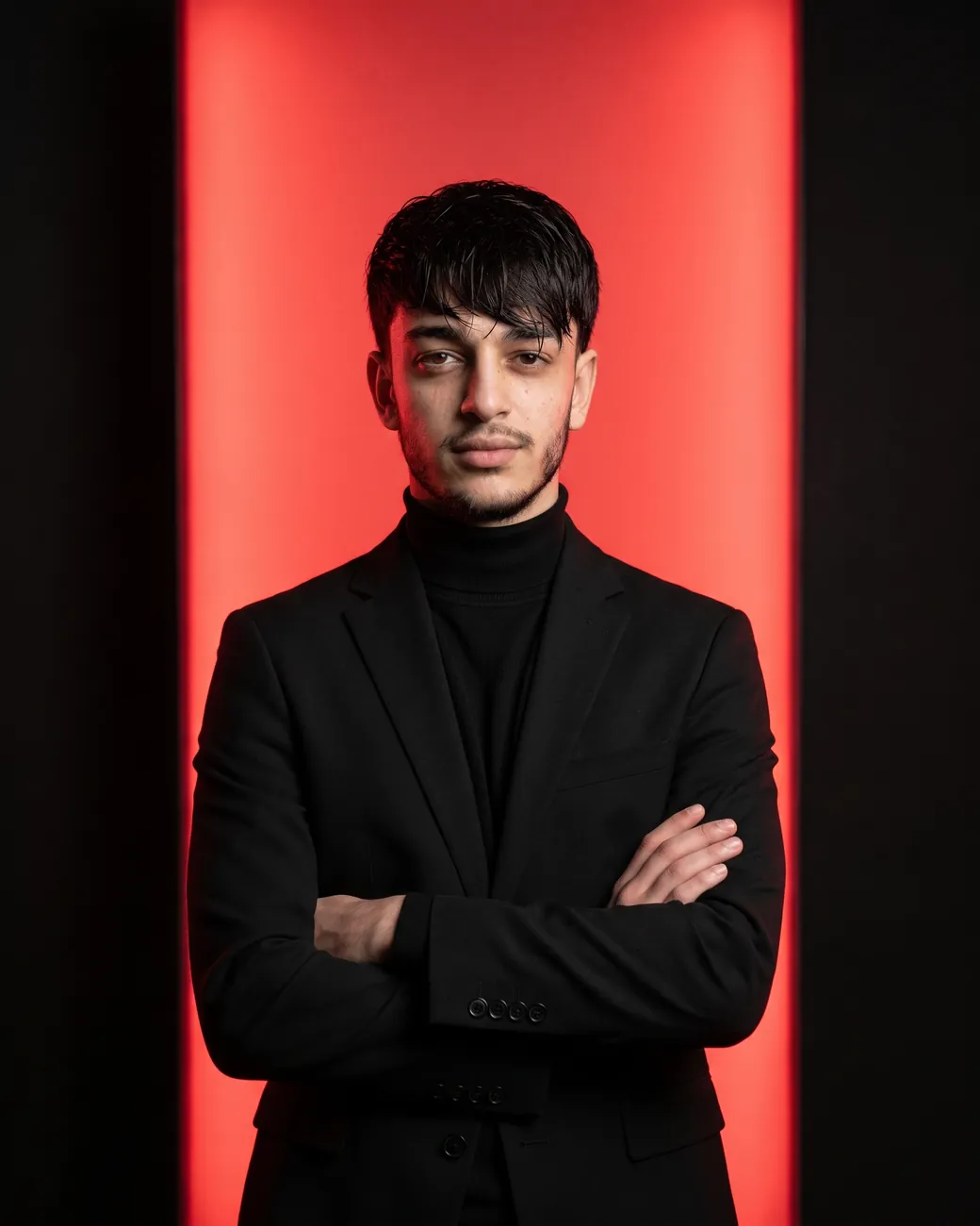 Rustam, standing in front of a lit red panel.